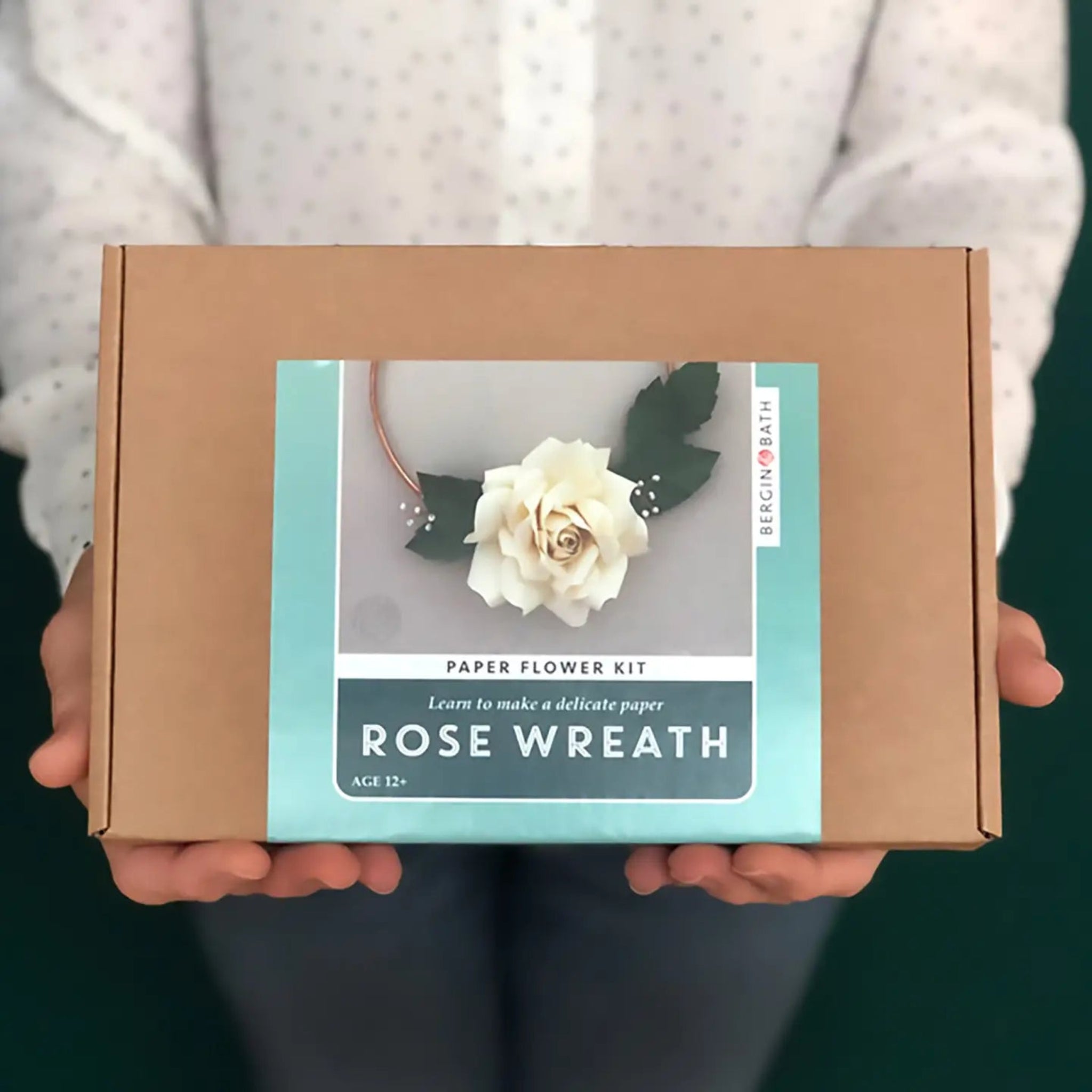 Person holding a 'Paper Flower Kit Rose Wreath' box